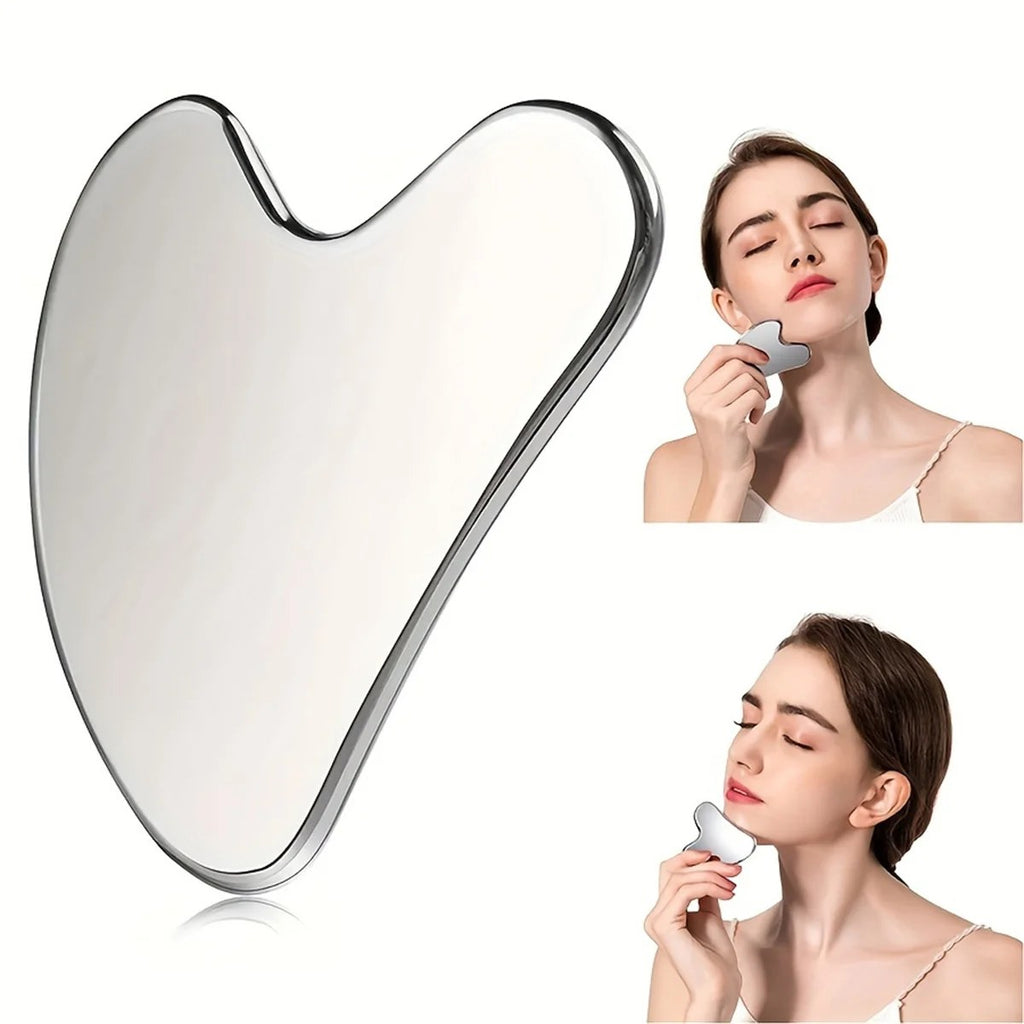 A woman gently massages her jawline and neck using a smooth, heart-shaped stainless steel gua sha tool.